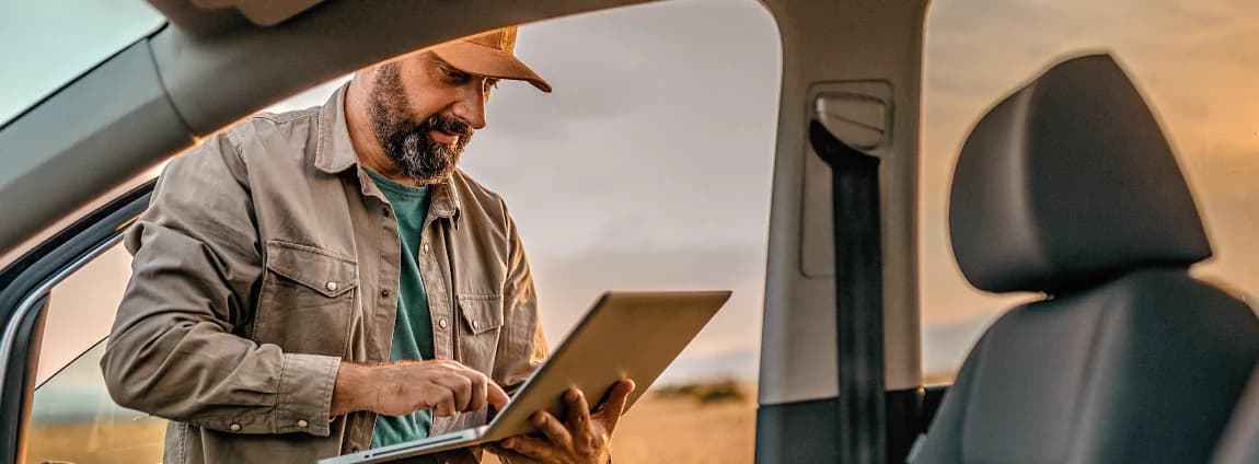 homem analisando dados do carro no computador em uma plantação