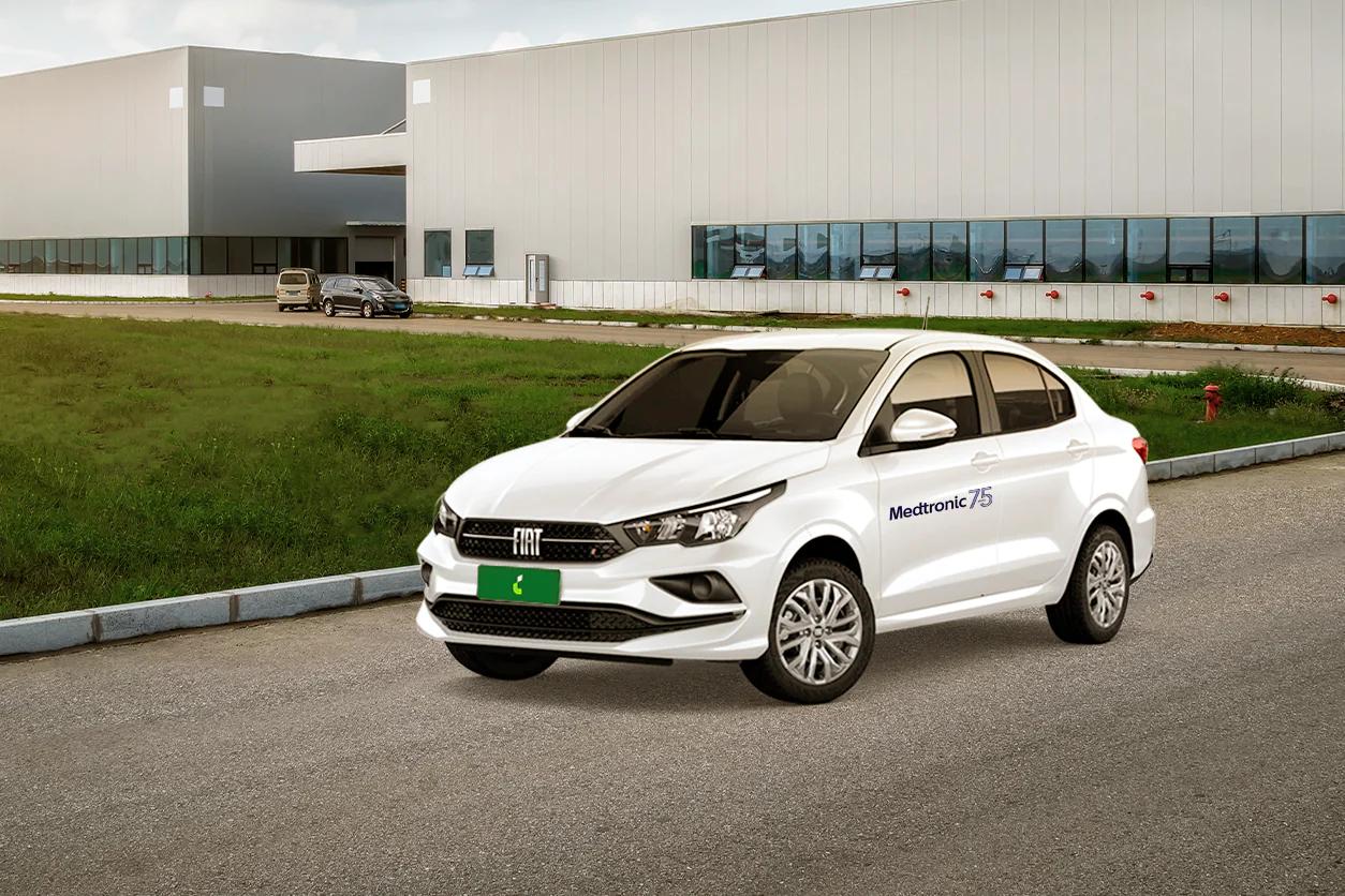 Foto carro branco da Fiat com logo da Medtronic na porta com um prédio de uma empresa ao fundo. Foto carro branco da Fiat com logo da Medtronic na porta com um prédio de uma empresa ao fundo.