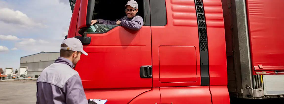 Motorista dentro do caminhão truck conversando com funcionário Motorista dentro do caminhão truck conversando com funcionário