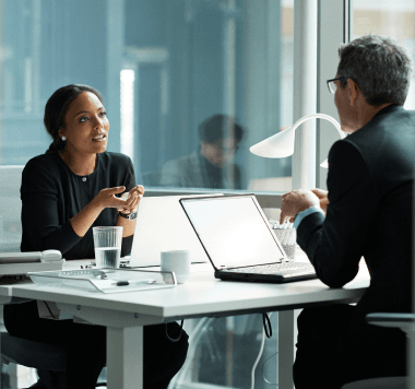 Imagem de um homem e uma mulher conversando sentados em um mesa de escritório Imagem de um homem e uma mulher conversando sentados em um mesa de escritório
